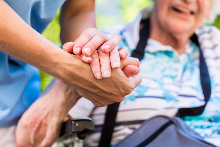 Ältere Frau im Rollstuhl wird von Pflegerin begleitet; das Diktat mit DNS comfort verschafft ihr zusätzliche Zeit mit ihrer Patientin